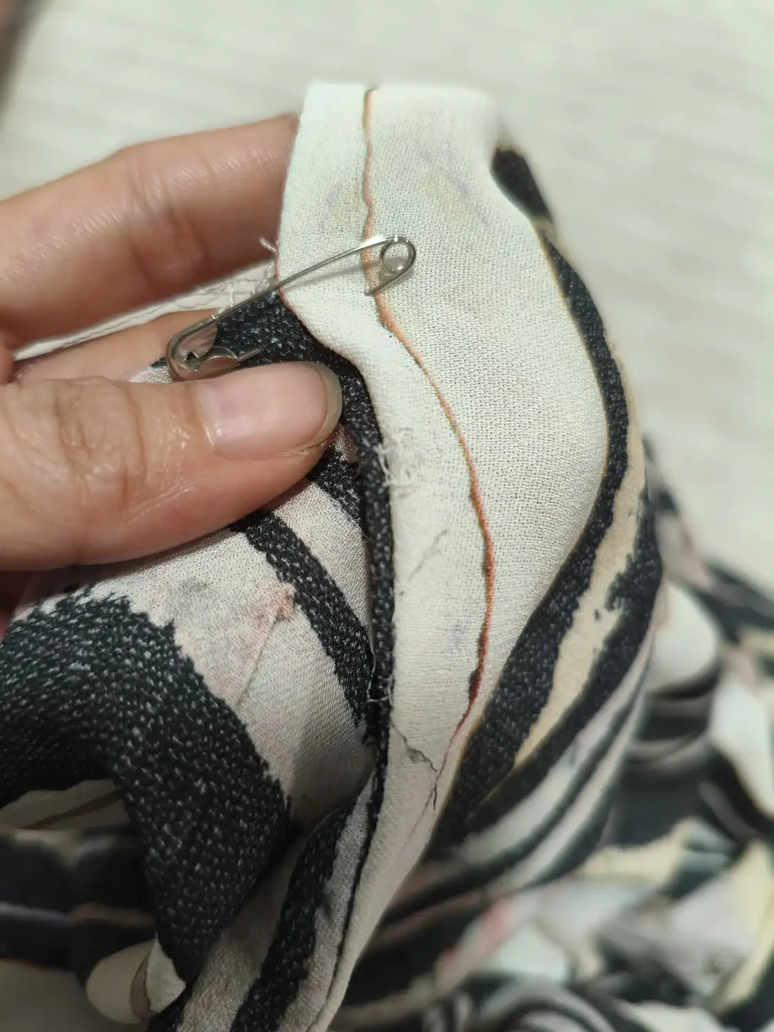 Safety pin holding a seam in place before a quick garment repair
