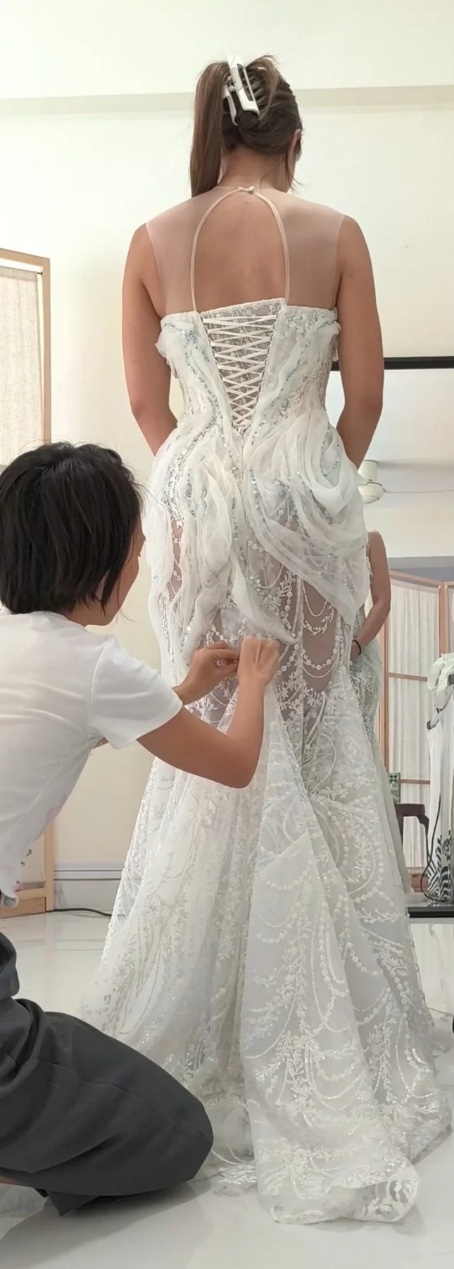 Seamstress fitting and adjusting the back of a wedding dress