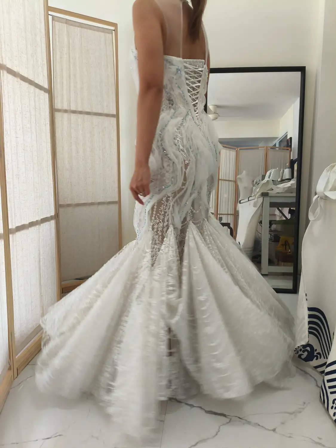 Lace mermaid wedding gown with its train spread across the fitting studio floor