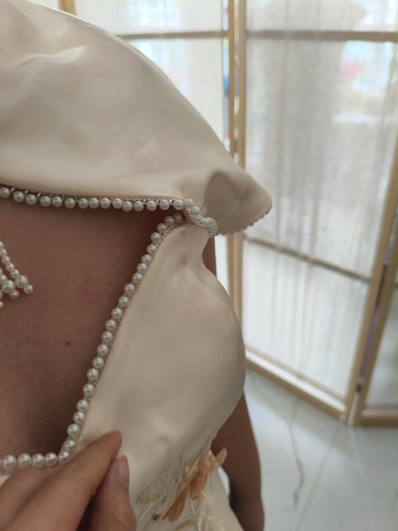 Hands adjusting pearl embellishment on a bridal gown