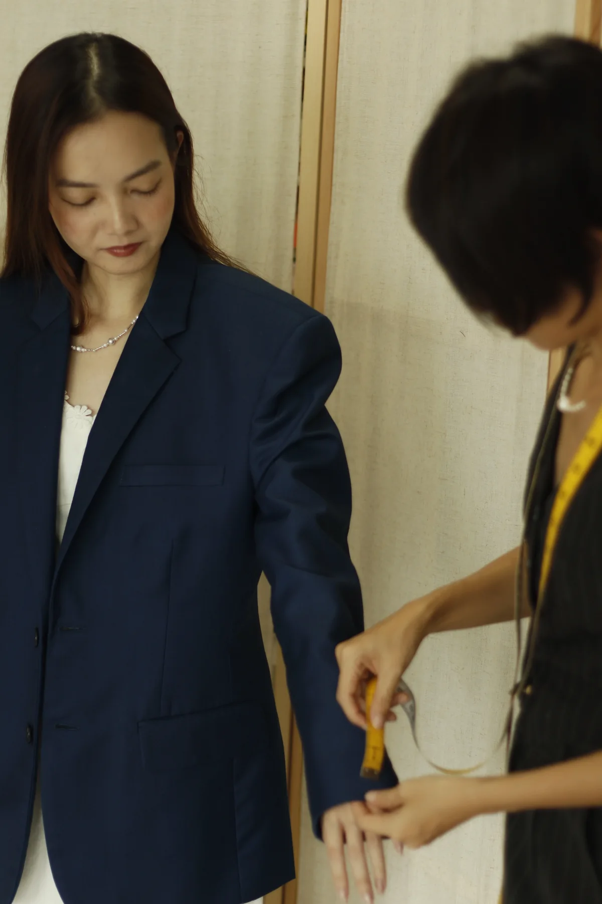 Tailor assessing a navy blazer during a fitting