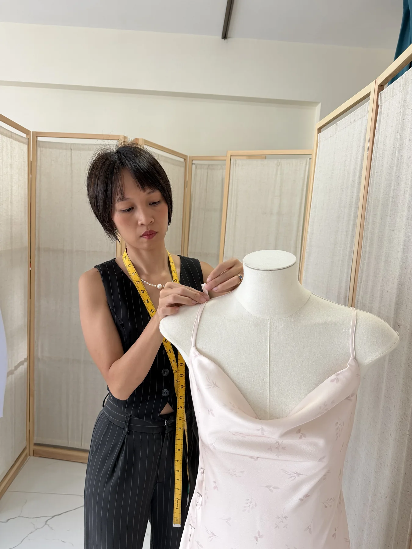 Tailor adjusting a floral dress on a mannequin during a fitting