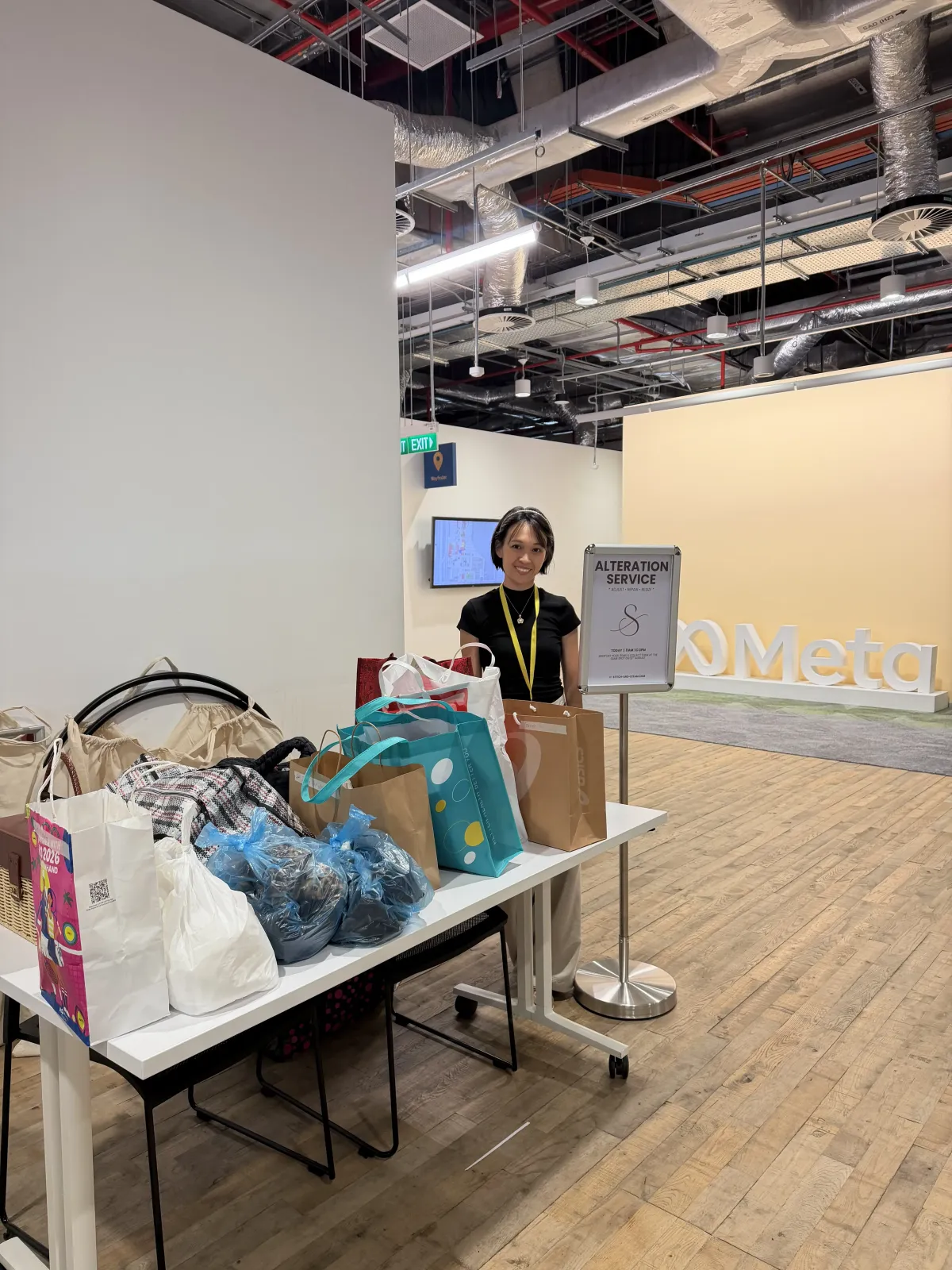 Stitch and Steam alteration service standee and staff member at a Meta office pop-up